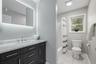 Vanity with an integrated rectangular sink, stone countertop, chrome faucet, and under-mirror lighting
