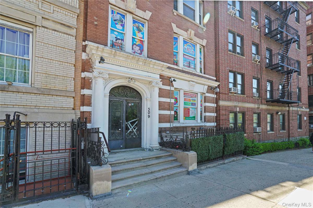 Brick facade building featuring a grand arched entryway with ornate wrought iron doors, flanked by decorative columns