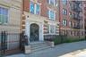 Brick facade building featuring a grand arched entryway with ornate wrought iron doors, flanked by decorative columns