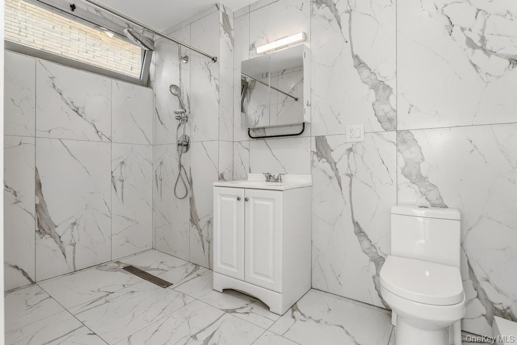 Bathroom featuring a marble finish shower, vanity, and marble tiled flooring
