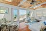Living area featuring wood-finish flooring, a vaulted wood-paneled ceiling with skylights, and a ceiling fan