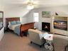 Bedroom featuring carpet flooring, vaulted ceiling, ceiling fan, and a warm lit fireplace