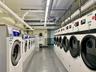 Laundry room Community laundry room featuring multiple front-loading washing machines, durable flooring, and overhead fluorescent lighting