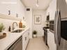 Sleek, modern galley kitchen featuring abundant cabinetry, generous countertop space, stainless steel appliances, and a clean, efficient layout. Ample