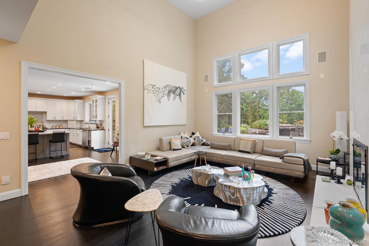 Living room with a towering ceiling, dark wood-style flooring, and recessed lighting