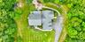 Expansive property featuring a multi-gabled roofline, a paved driveway, and a stone patio