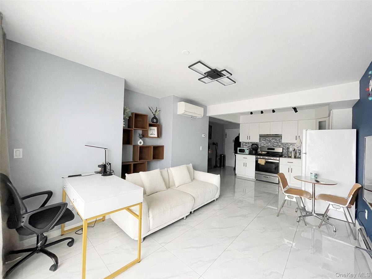 Living area featuring light marble finish floors, an AC wall unit, and an office area