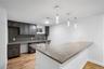 Kitchen featuring a peninsula, tasteful backsplash, hanging light fixtures, light wood-style floors, and light stone counters