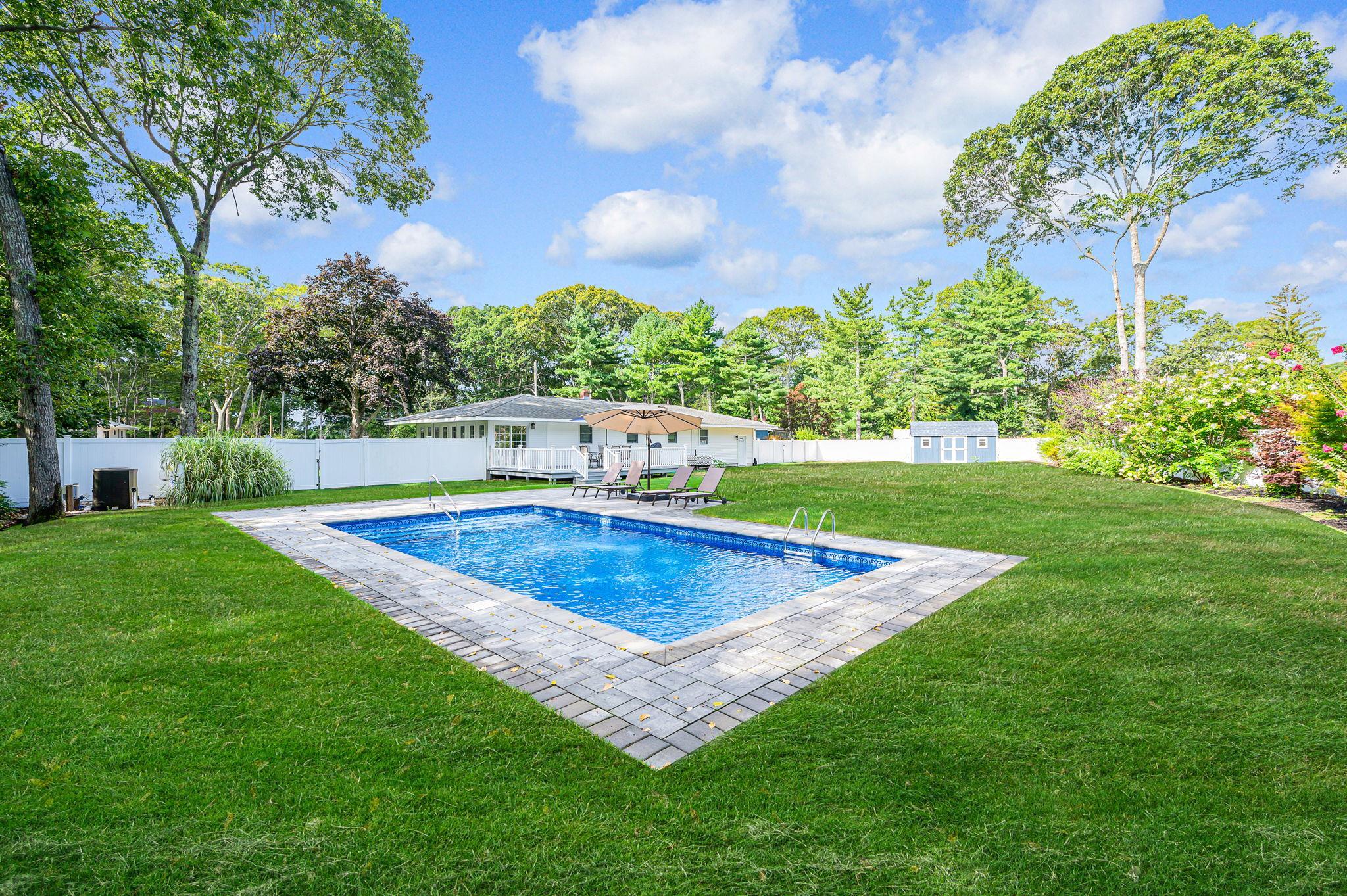 View of swimming pool with a fenced backyard, an outbuilding, a patio area, and view of scattered trees