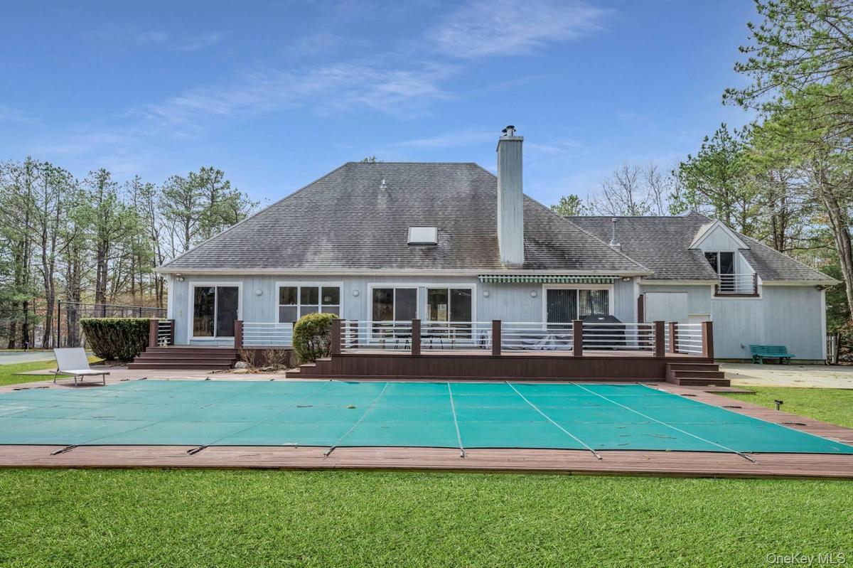 Back of house with a yard, a chimney, a fenced in pool, and a wooden deck