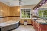Full bathroom featuring tile walls, a tub with jets, double vanity, ceiling fan, and marble finish flooring