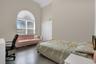 Bedroom with high vaulted ceiling and wood finished floors