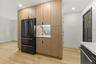 Integrated kitchen cabinetry featuring wood-finish panels and a built-in black refrigerator