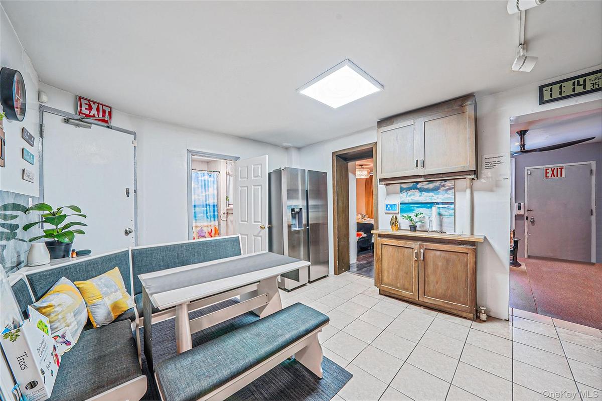 Kitchen with stainless steel refrigerator with ice dispenser, brown cabinetry, and light countertops