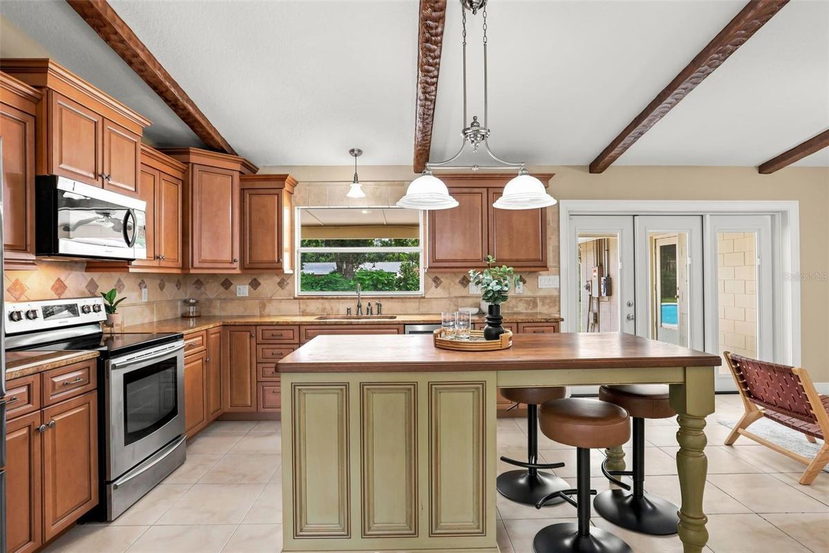 Rich wood cabinetry, abundant counter space, a center island, SLEEK TILE BACKSPLASH, stainless steel appliances, a closet pantry, and a spacious Break