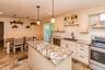 Kitchen featuring a central island with a stone countertop, stainless steel appliances, subway tile backsplash, and cream-colored cabinetry with displ