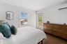 Bedroom with an AC wall unit and wood finished floors