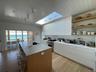 Kitchen with high end stainless steel range, a kitchen breakfast bar, a skylight, a kitchen island with sink, and a sink