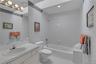 Full bathroom featuring a single vanity with an integrated sink, a large mirror, a chrome multi-bulb light fixture, a toilet, and a combined tub and s