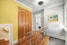 Hallway with wood-finish flooring, bi-fold closet doors, a decorative ceiling light fixture, and a metal railing
