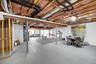 Spacious unfinished basement with exposed wooden joists, concrete flooring, and metal support columns