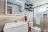 Basement Bathroom (Legal) featuring a white vanity with an integrated sink, tri-panel mirrored medicine cabinet, and a frameless glass shower enclosur