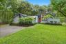 Mid-century home with a front yard, decorative driveway, and view of scattered trees