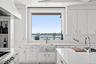 Kitchen featuring a sink, white cabinetry, wall chimney exhaust hood, a water view, and range