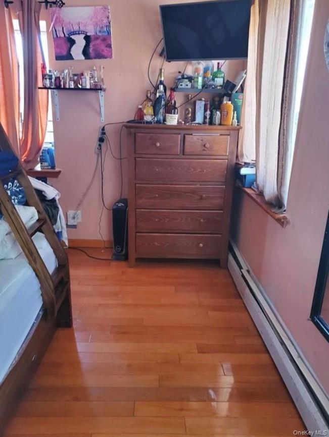 Bedroom with a baseboard radiator and light wood-style flooring