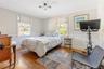 Bedroom featuring a wainscoted wall, multiple windows, and wood-type flooring