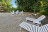 Expansive outdoor area featuring gravel ground cover, stepping stones, and mature trees providing natural shade