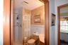Full bathroom featuring a walk-in shower with tiled walls and built-in corner shelves, a toilet, and a vanity with a sink