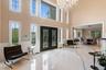 Foyer featuring a chandelier, french doors, light marble finish floors, a decorative wall, and a towering ceiling