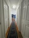 Hallway featuring wood-finish flooring, white paneled doors, and a flush-mount ceiling light