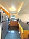 Kitchen featuring appliances with stainless steel finishes, a peninsula, dark stone countertops, brown cabinetry, and dark tile patterned floors