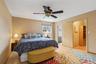 Bedroom featuring light wood finished floors, ensuite bath, and ceiling fan