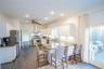 Kitchen with stainless steel appliances, white cabinetry, a sink, a peninsula, and wall chimney exhaust hood
