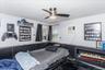 Room featuring a ceiling fan with integrated lighting, white walls, and dark wainscoting