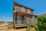 Cedar shake exterior with a covered porch and deck featuring a wooden railing