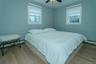 Bedroom with ceiling fan, light hardwood / wood-style floors, baseboard heating, and multiple windows