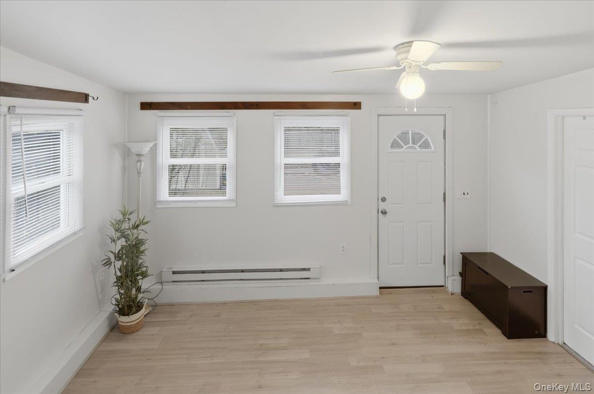 Entryway with light wood finished floors, a baseboard radiator, and a ceiling fan