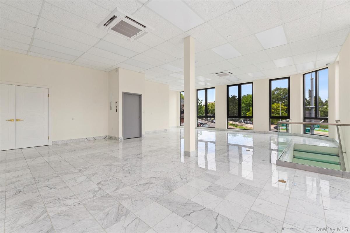 Unfurnished room featuring a paneled ceiling, light marble finish flooring, and baseboards