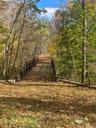 Pivate driveway leads to bridge over waterfall and beyond to building envelope
