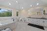 Full bathroom featuring tile walls, a jetted tub, double vanity, wainscoting, and a bidet