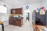 Kitchen featuring freestanding refrigerator, light tile patterned floors, dark brown cabinets, and dark stone counters