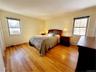 Bedroom featuring light wood-style floors, multiple windows, and a baseboard heating unit