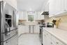 Kitchen featuring appliances with stainless steel finishes, white cabinets, light countertops, range hood, and recessed lighting