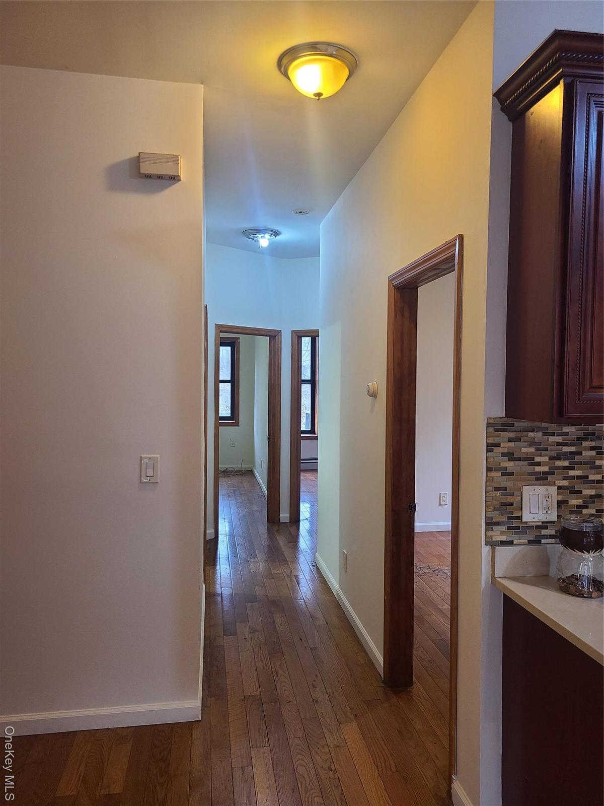 Hall with dark wood-type flooring and baseboards