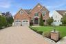 Brick exterior with a gabled roofline, two-car garage, bay window, and a paver driveway