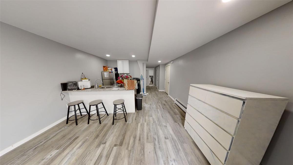 Kitchen featuring white cabinetry, a baseboard radiator, a kitchen breakfast bar, light hardwood / wood-style floors, and kitchen peninsula